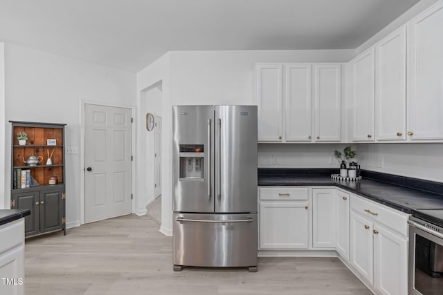 kitchen featuring dark countertops, light wood-type flooring, white cabinetry, and stainless steel appliances