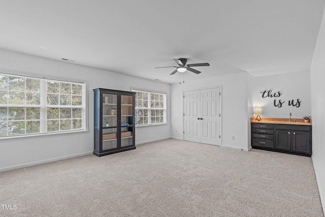 unfurnished bedroom with visible vents, a sink, carpet floors, a closet, and baseboards