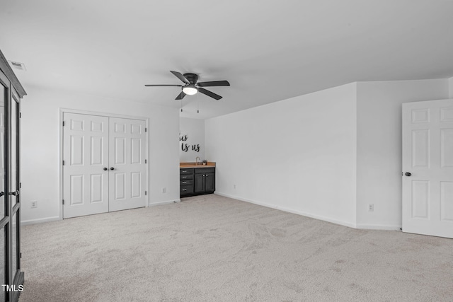 unfurnished bedroom featuring visible vents, light carpet, a sink, a closet, and baseboards