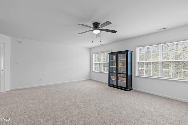 spare room with baseboards, a ceiling fan, visible vents, and carpet