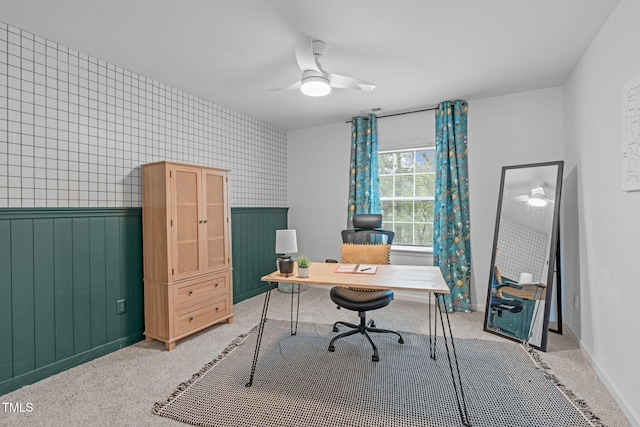 office space featuring baseboards, a wainscoted wall, light colored carpet, and ceiling fan