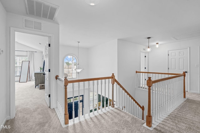 corridor with visible vents, attic access, carpet flooring, and an upstairs landing