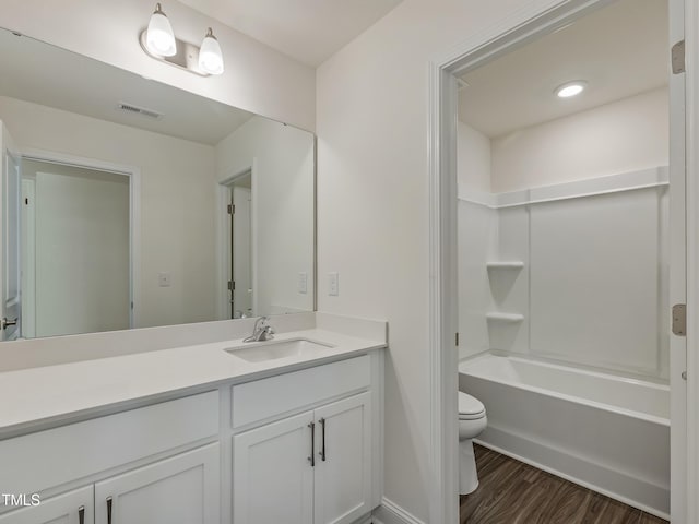 bathroom with vanity, toilet, baseboards, wood finished floors, and visible vents
