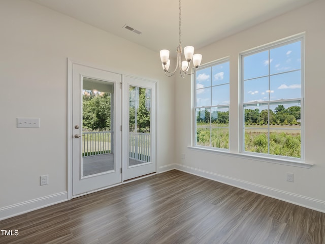 unfurnished dining area featuring baseboards, dark wood-type flooring, a chandelier, and visible vents