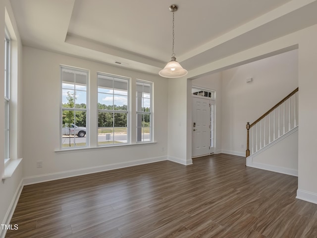 entryway featuring a raised ceiling, baseboards, stairs, and dark wood-style floors