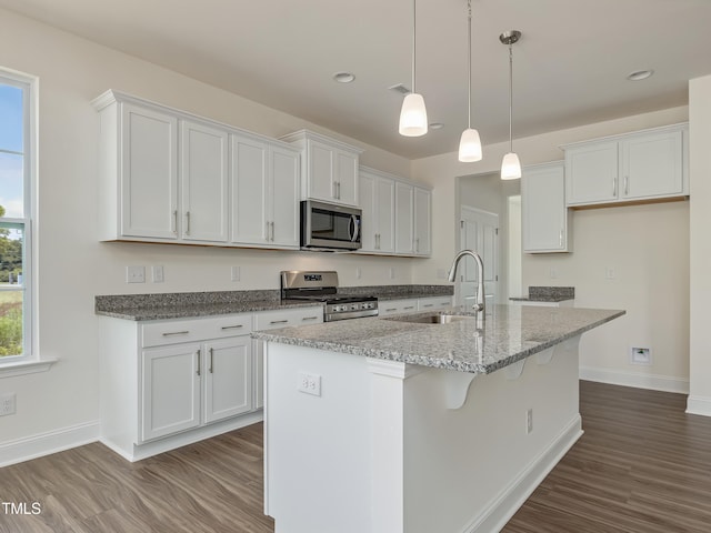 kitchen with baseboards, dark wood-type flooring, white cabinets, a sink, and stainless steel appliances