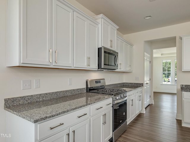 kitchen with recessed lighting, white cabinets, light stone counters, dark wood finished floors, and stainless steel appliances