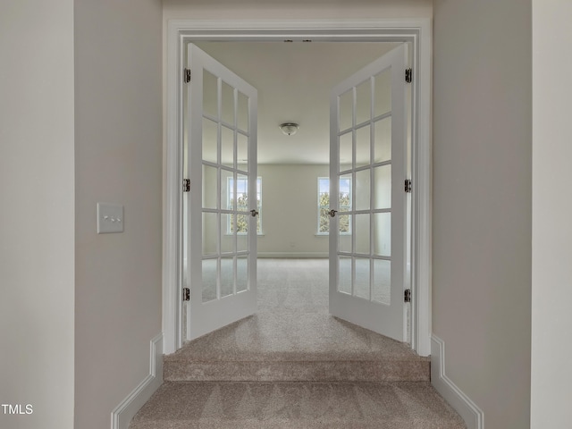 corridor featuring french doors, baseboards, and carpet flooring