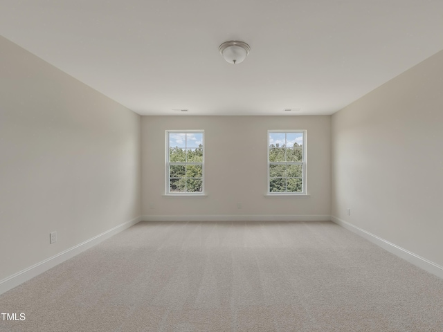 unfurnished room with baseboards and light carpet