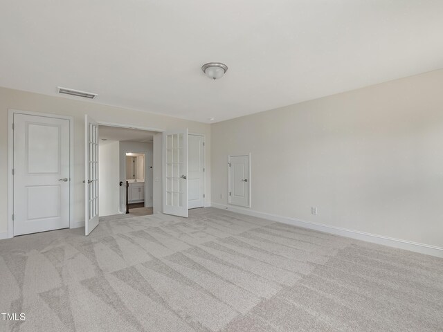 unfurnished bedroom with light colored carpet, baseboards, visible vents, and french doors
