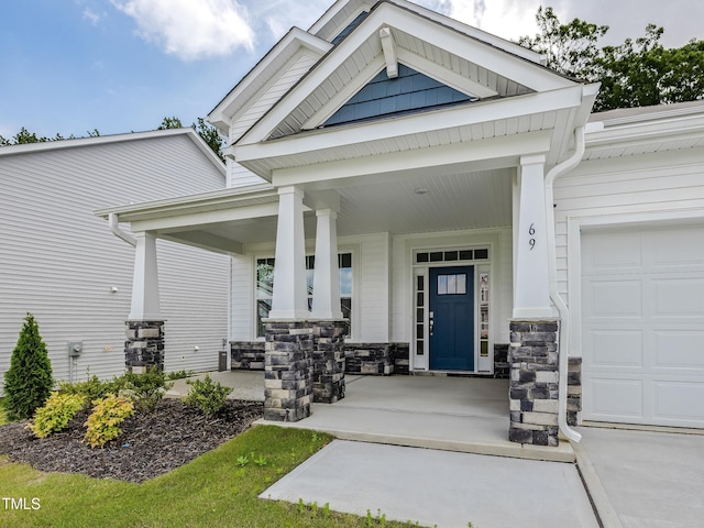 property entrance with a porch, an attached garage, and stone siding