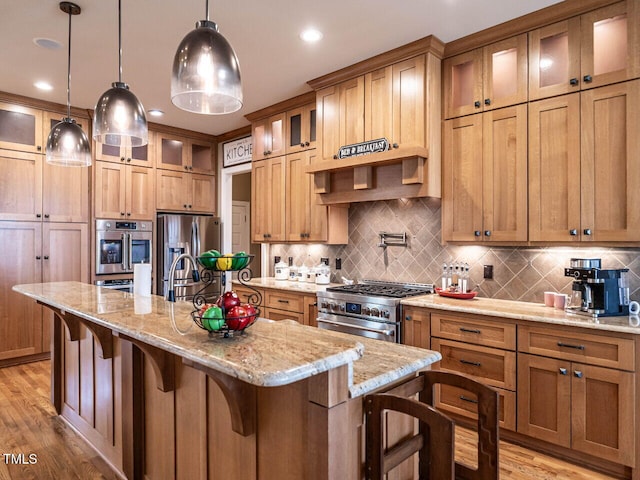 107 Bella Casa Way, Clayton, NC 27527 - kitchen featuring light wood finished floors, a center island with sink, appliances with stainless steel finishes, pendant lighting, and a kitchen breakfast bar