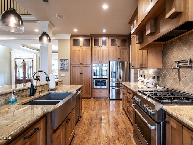 107 Bella Casa Way, Clayton, NC 27527 - kitchen with a sink, pendant lighting, light wood-style flooring, appliances with stainless steel finishes, and brown cabinetry