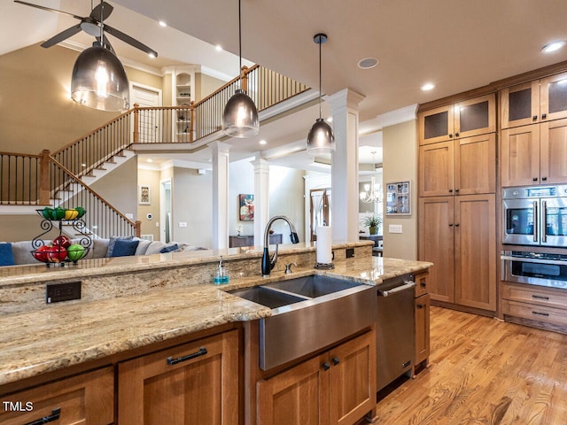 107 Bella Casa Way, Clayton, NC 27527 - kitchen featuring a sink, brown cabinets, open floor plan, stainless steel appliances, and ornate columns