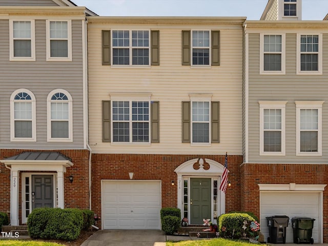 townhome / multi-family property featuring an attached garage, brick siding, and driveway