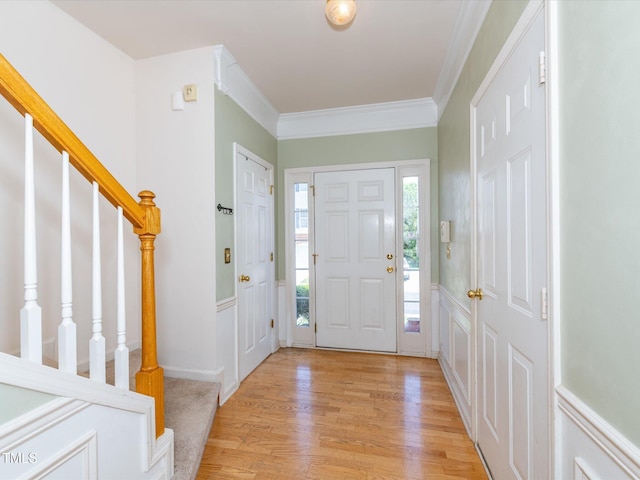 entryway with stairway, light wood-style floors, and crown molding