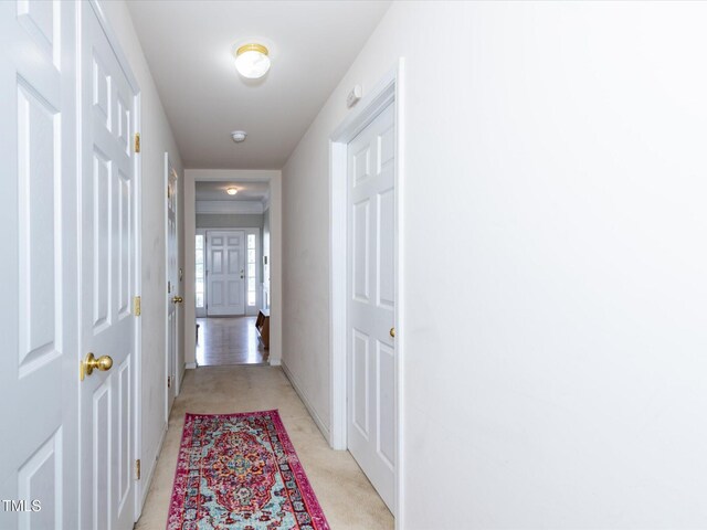 hallway with light colored carpet and baseboards