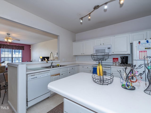 kitchen featuring white appliances, a sink, a peninsula, light countertops, and white cabinets