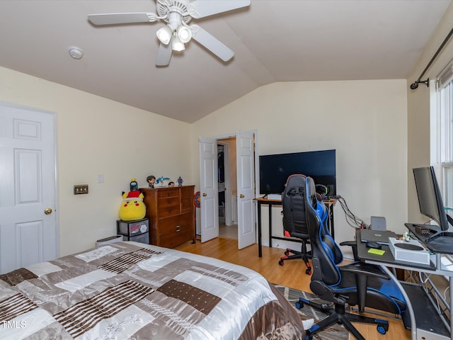 bedroom with vaulted ceiling, light wood-type flooring, a desk, and ceiling fan
