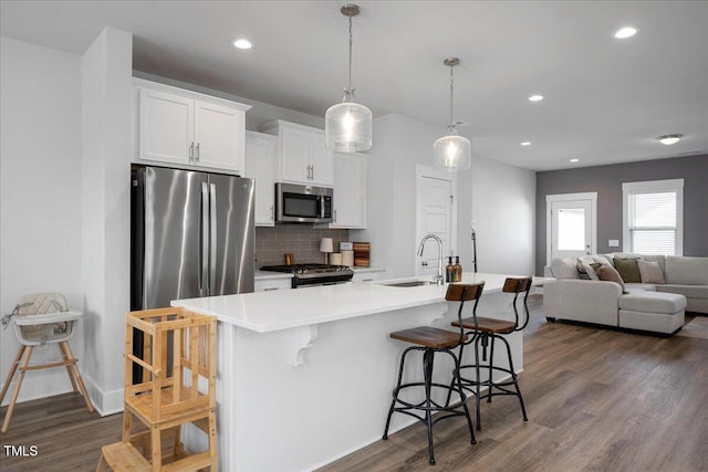 305 Wash Hollow Dr, Wendell, NC 27591 - kitchen with a sink, a breakfast bar area, stainless steel appliances, decorative backsplash, and dark wood-style flooring