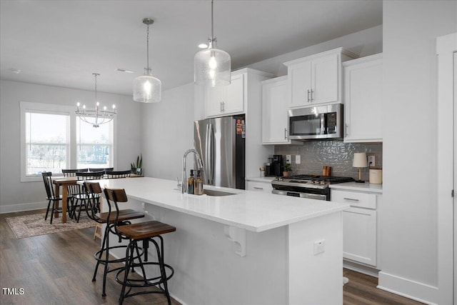305 Wash Hollow Dr, Wendell, NC 27591 - kitchen with dark wood-style flooring, a kitchen island with sink, stainless steel appliances, and a breakfast bar