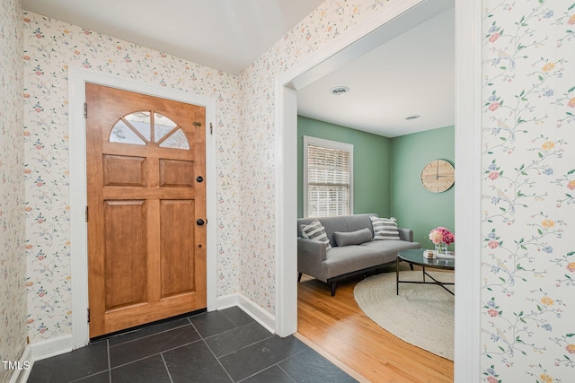 entrance foyer featuring baseboards, wallpapered walls, and dark wood-type flooring