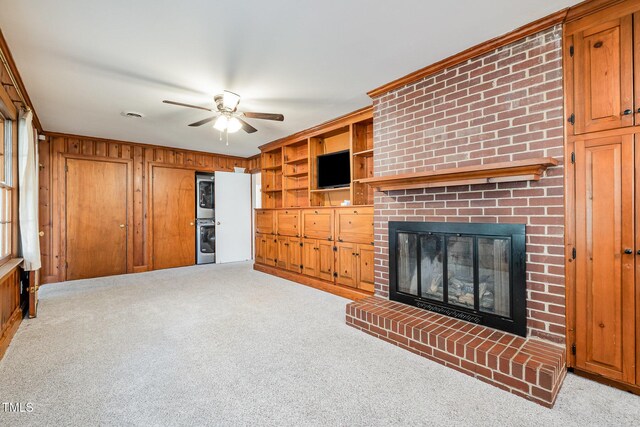 unfurnished living room featuring a fireplace, ornamental molding, ceiling fan, and carpet