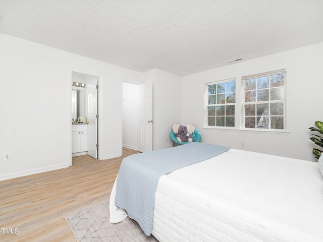 106 Mingocrest Dr, Knightdale, NC 27545 - bedroom with baseboards, a textured ceiling, connected bathroom, visible vents, and light wood-style flooring
