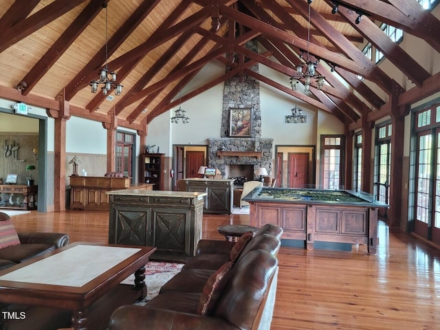 living area with a stone fireplace, light wood-style floors, beam ceiling, and wood ceiling