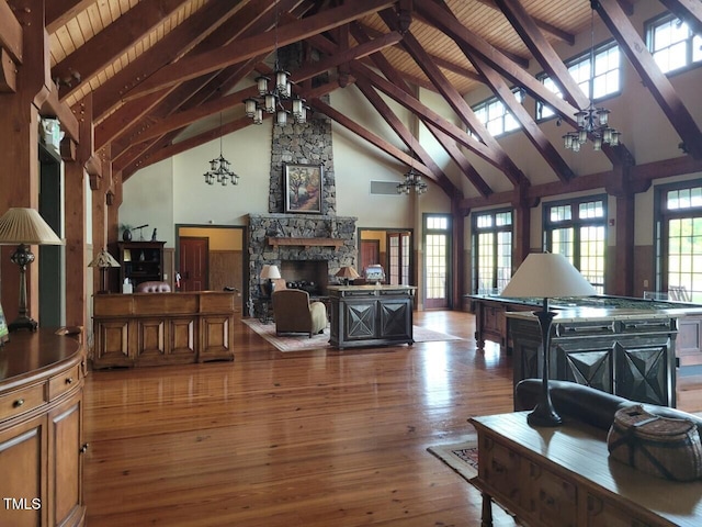 living area with a fireplace, high vaulted ceiling, beamed ceiling, a chandelier, and hardwood / wood-style floors