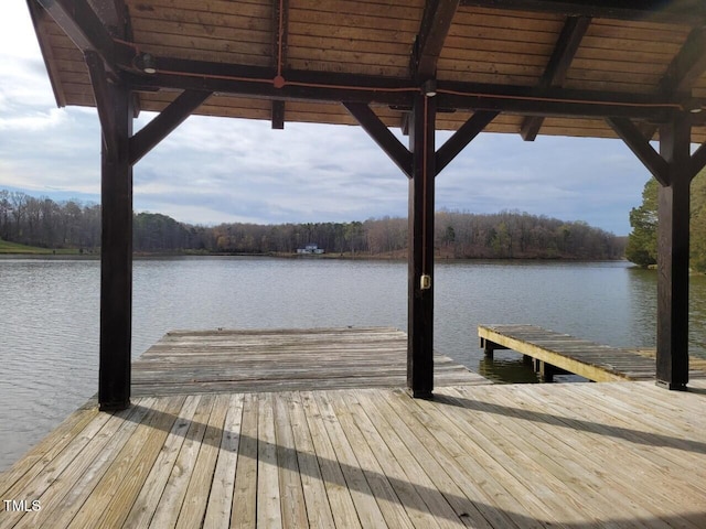 view of dock featuring a water view and a forest view