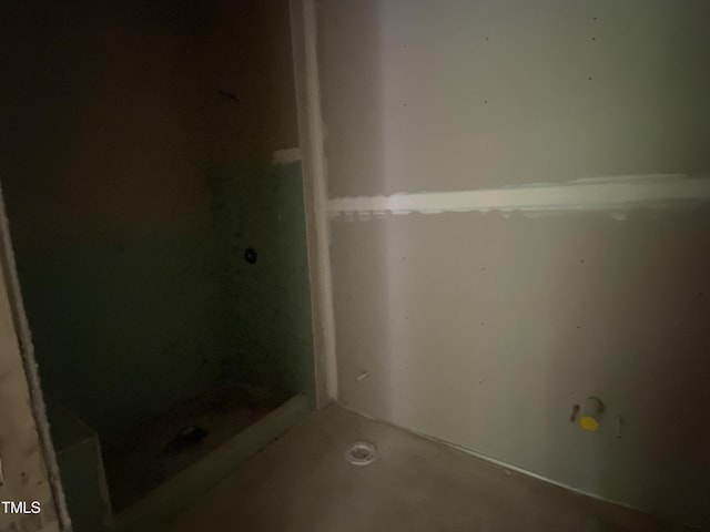 bathroom with concrete flooring and a stall shower