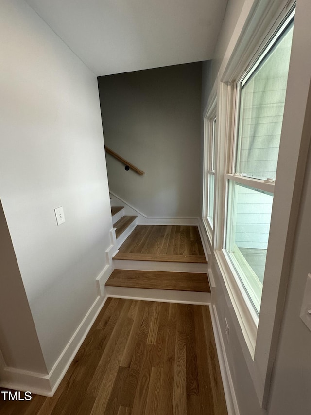 staircase featuring baseboards and wood finished floors