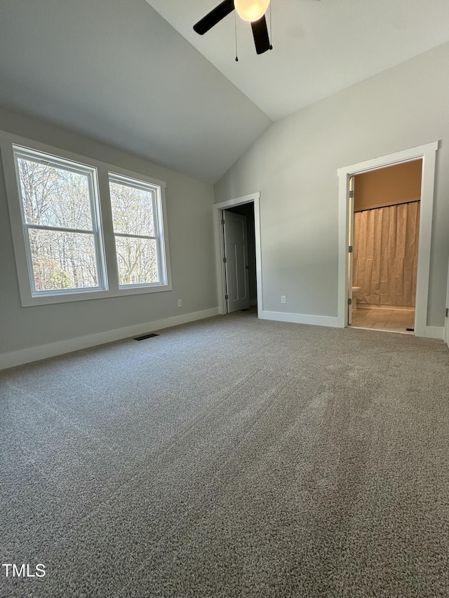 interior space featuring carpet floors, lofted ceiling, ensuite bathroom, baseboards, and visible vents