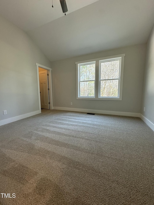 empty room with vaulted ceiling, baseboards, carpet floors, visible vents, and ceiling fan