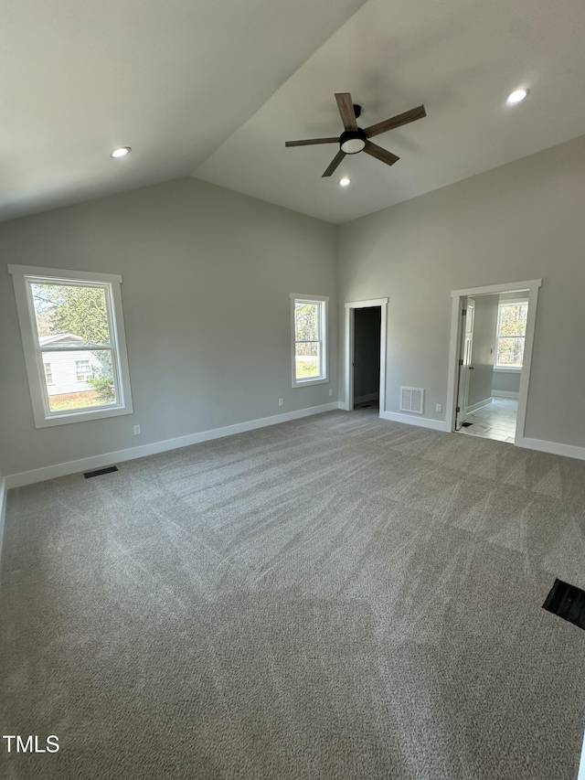 carpeted empty room featuring baseboards, ceiling fan, visible vents, and vaulted ceiling
