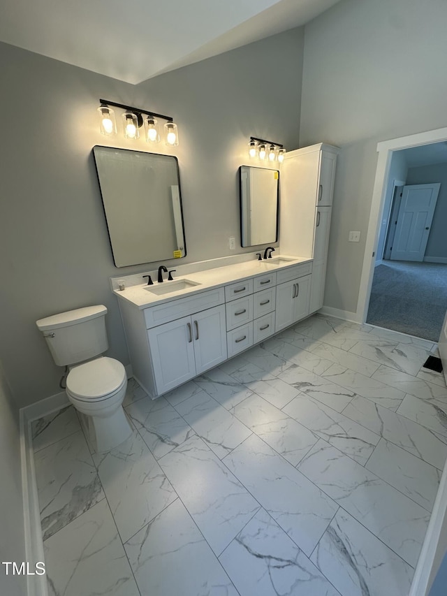 full bath with marble finish floor, a sink, double vanity, and baseboards