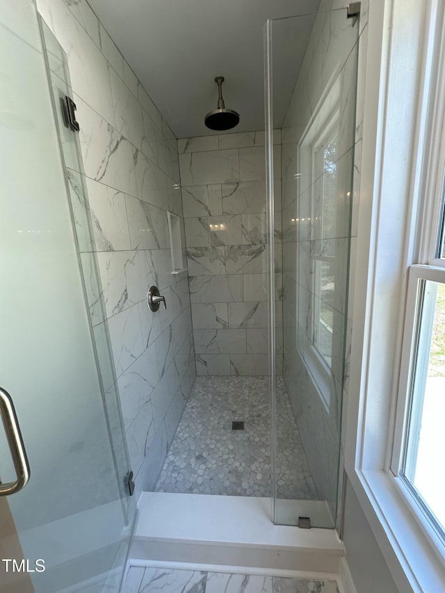 bathroom with a stall shower and marble finish floor