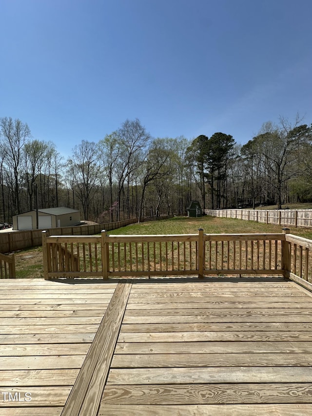 wooden terrace featuring fence, an outdoor structure, and a yard