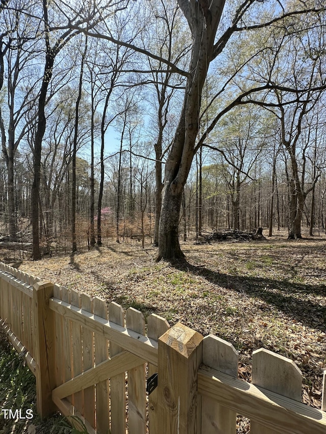view of yard featuring a wooded view and fence