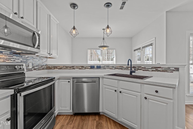 kitchen featuring white cabinets, visible vents, wood finished floors, stainless steel appliances, and a sink
