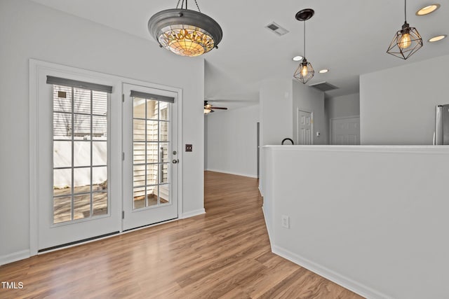 interior space with wood finished floors, baseboards, ceiling fan, and visible vents
