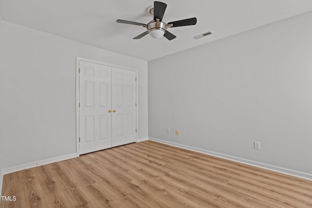 unfurnished bedroom with a closet, visible vents, baseboards, a ceiling fan, and light wood-style floors