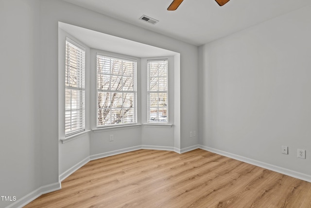 empty room with baseboards, visible vents, wood finished floors, and ceiling fan