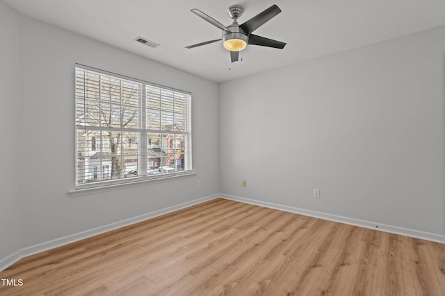 spare room featuring baseboards, light wood-style flooring, visible vents, and a ceiling fan