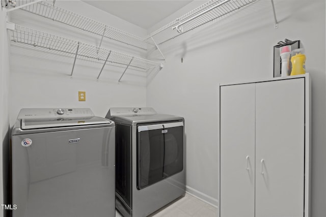 clothes washing area with separate washer and dryer, baseboards, and laundry area