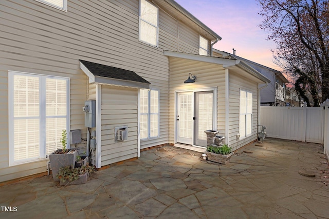 back of property at dusk with fence and a patio area