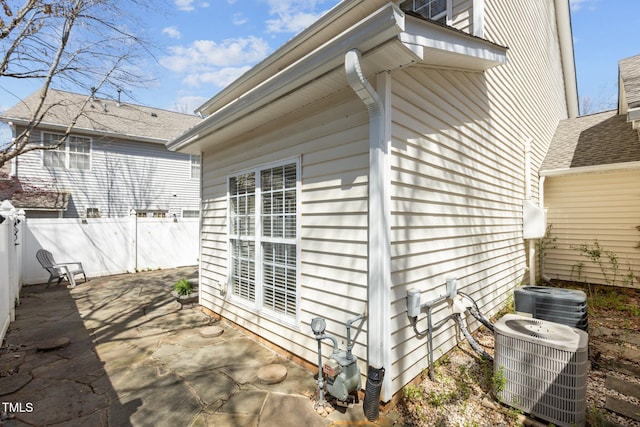view of property exterior featuring central AC, fence, and a patio