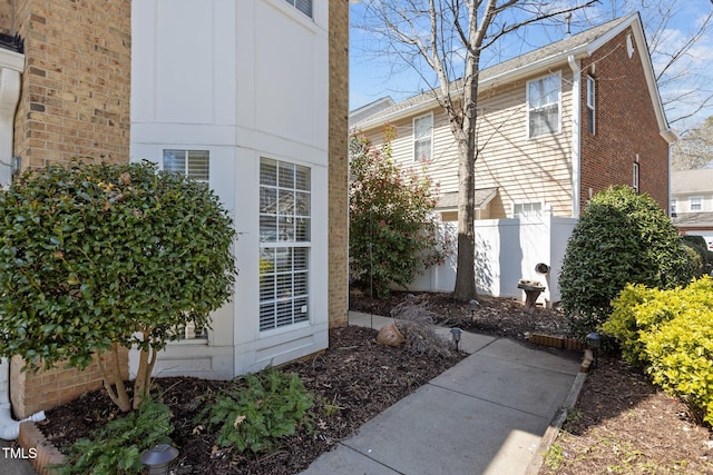 view of side of property featuring brick siding and fence