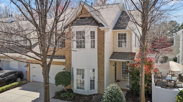 view of front facade with fence, driveway, and roof with shingles